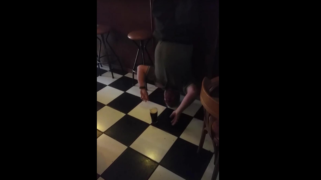Man drinks Guinness while standing on head